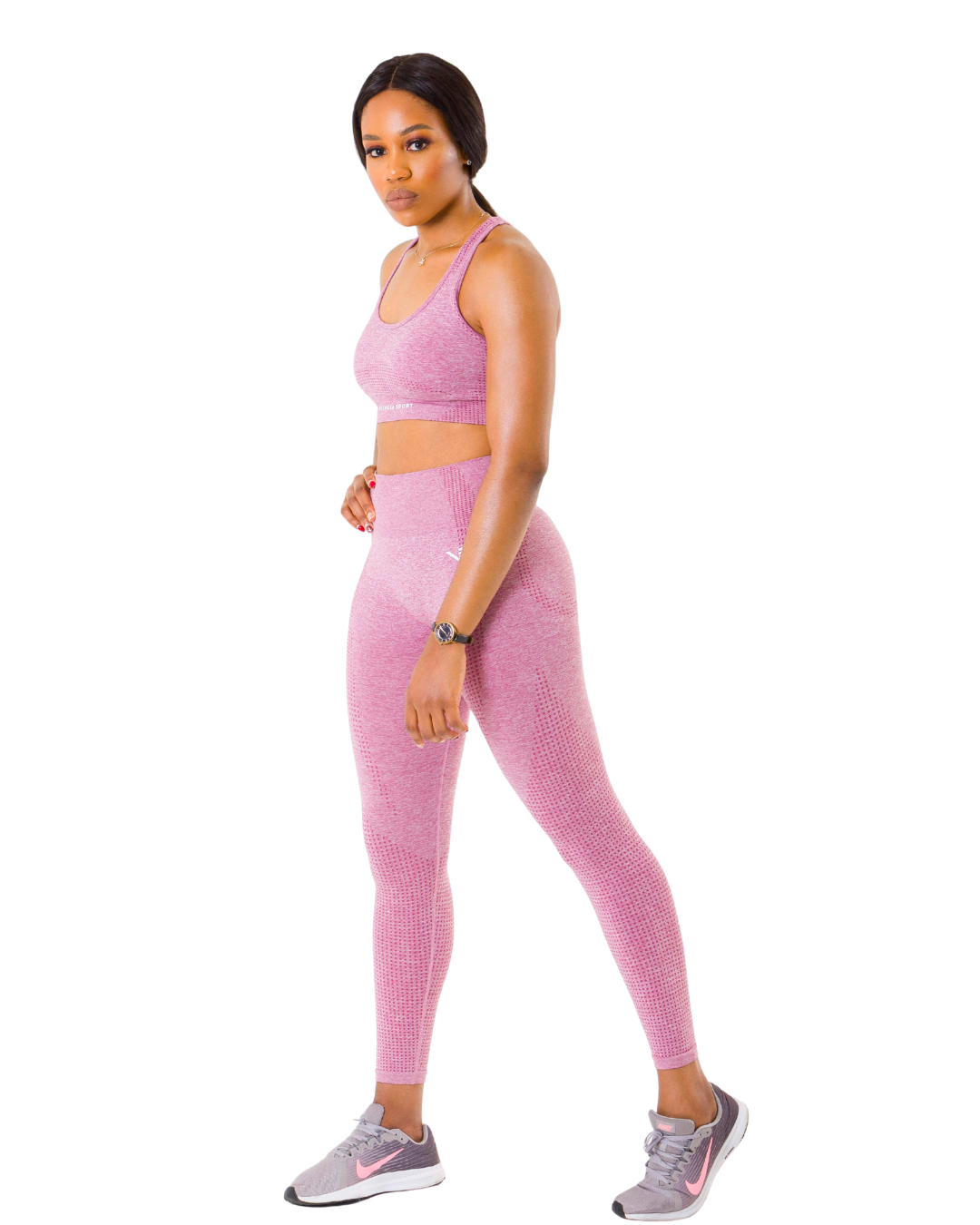 Sandra, certified postpartum fitness coach, standing confidently in pink workout attire